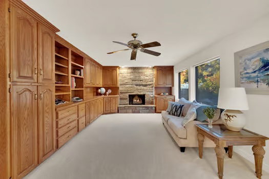 Family Room section of large open Great Room featuring custom wood cabinets & fireplace and lots of windows with  fantastic back-yard view