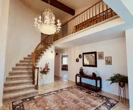 Two-Story grand entryway featuring elegant curved stairway and high-quality vintage chandelier.