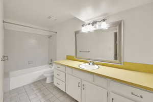 Basement Apartment Bathroom with extra wide vanity, shower / bath combination, large mirror and light tile patterned flooring.