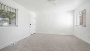 Unfurnished room featuring light colored carpet, ceiling fan, and a textured ceiling