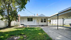 Rear view of house with a lawn, a chimney, a carport, and entry steps