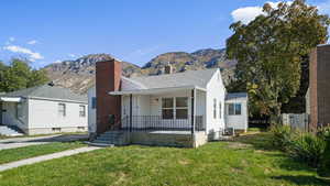 Bungalow with a chimney, covered porch, a mountain view, and roof with shingles