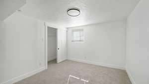 Unfurnished bedroom featuring light colored carpet, a closet, and a textured ceiling