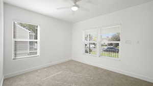 Empty room with plenty of natural light, carpet, and a ceiling fan