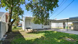 Back of property with a lawn, a carport, and entry steps