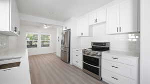 Kitchen featuring decorative backsplash, stainless steel appliances, white cabinets, light wood finished floors, and recessed lighting