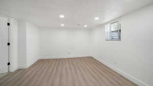 Basement with light wood-style floors, recessed lighting, and a textured ceiling