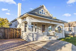 View of front of property with covered porch, brick siding, a chimney, and a shingled roof