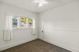 Spare room featuring dark carpet and a ceiling fan