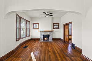 Unfurnished living room with arched walkways, dark wood-style flooring, and healthy amount of natural light