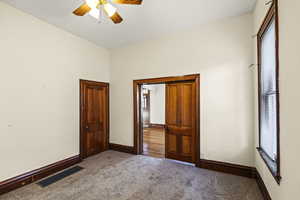 Unfurnished bedroom with carpet floors, multiple windows, and ceiling fan