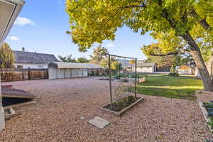 Fenced backyard featuring a vegetable garden and an outbuilding