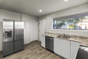 Kitchen featuring appliances with stainless steel finishes, light stone countertops, dark wood-style floors, white cabinets, and recessed lighting
