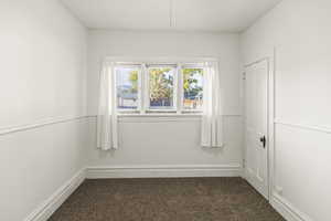 Spare room with dark colored carpet and baseboards
