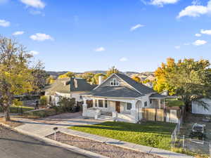 View of front of house with covered porch, a chimney, driveway, roof with shingles, and a mountain view