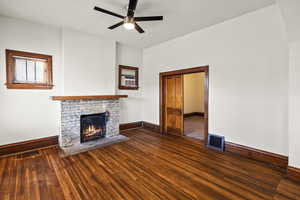 Unfurnished living room with a fireplace, a ceiling fan, and dark wood-style floors