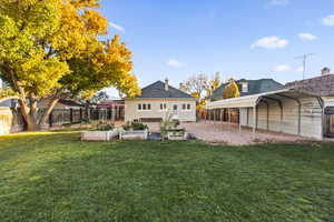 Fenced backyard with a detached carport and a vegetable garden