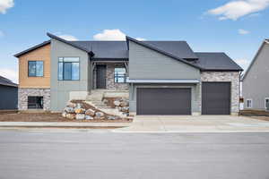 Contemporary home with stone siding, concrete driveway, a shingled roof, and an attached garage