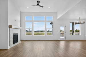 Unfurnished living room with wood finished floors, plenty of natural light, a tiled fireplace, and recessed lighting