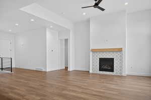 Unfurnished living room with recessed lighting, light wood-type flooring, a tiled fireplace, and ceiling fan