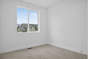 Carpeted spare room with baseboards