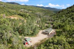 Aerial view of property and surrounding area featuring a forest and a mountain backdrop.