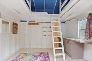 Inside the bunkhouse. Cabinets on the right. A few decorative shelves between the wall slats.