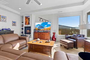 Living room with light wood-style flooring, recessed lighting, a glass covered fireplace, and a ceiling fan