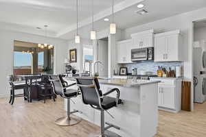 Kitchen featuring a kitchen breakfast bar, hanging light fixtures, backsplash, light wood-style floors, and recessed lighting