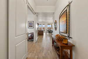 Corridor with light wood-type flooring and a barn door