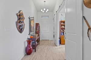Hallway featuring a barn door, light wood-type flooring, and a chandelier