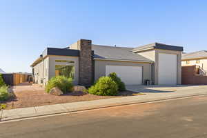 Contemporary house featuring an attached garage, stucco siding, driveway, and a tiled roof