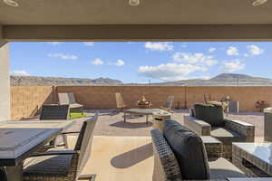 Fenced backyard featuring a patio area, a mountain view, a fire pit, and outdoor dining space