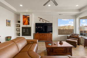 Living area with wood finished floors, ceiling fan, a large fireplace, and recessed lighting