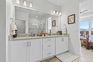 Ensuite bathroom with double vanity, a stall shower, light wood finished floors, and a ceiling fan