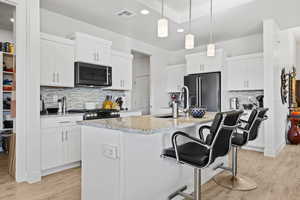 Kitchen with tasteful backsplash, a kitchen breakfast bar, recessed lighting, light wood-style flooring, and light stone counters