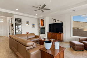 Living room with light wood-type flooring, a ceiling fan, built in features, and recessed lighting