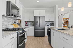 Kitchen featuring a barn door, premium appliances, white cabinetry, backsplash, and recessed lighting