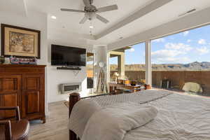 Bedroom featuring access to exterior, wood finished floors, a fireplace, recessed lighting, and a ceiling fan