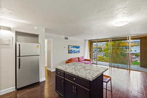 Kitchen with light countertops, a wall of windows, freestanding refrigerator, wood tiled floors, and open floor plan