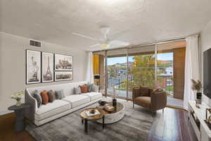 Virtually staged living area featuring expansive windows, dark wood-style flooring, a textured ceiling, and ceiling fan