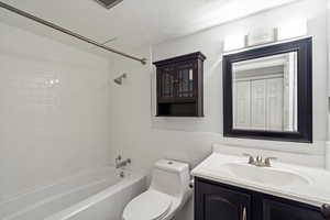 Full bath with vanity, washtub / shower combination, a textured ceiling, tile walls, and a wainscoted wall