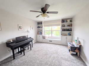 Living area featuring light carpet, ceiling fan, and built in shelves