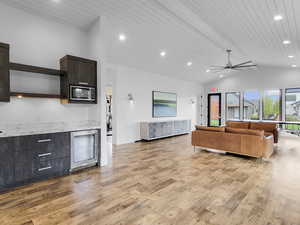 Living room with lofted ceiling, wine cooler, light wood-style floors, wooden ceiling, and recessed lighting