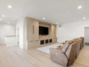 Living area with light wood-style flooring and recessed lighting