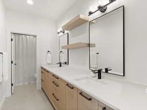 Full bath with double vanity, curtained shower, recessed lighting, and light tile patterned floors