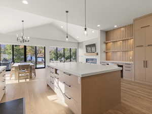 Kitchen with modern cabinets, pendant lighting, open shelves, lofted ceiling, and light wood-style flooring