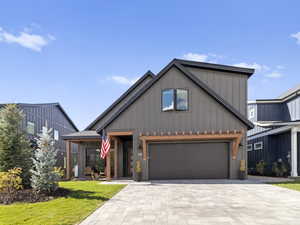 Modern inspired farmhouse featuring decorative driveway, board and batten siding, a front yard, and a garage