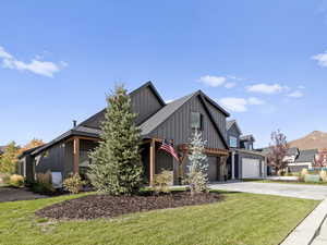 View of front of property with board and batten siding, concrete driveway, a front yard, a garage, and a mountain view
