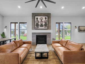 Living area with plenty of natural light, recessed lighting, a tiled fireplace, wooden ceiling, and wood finished floors
